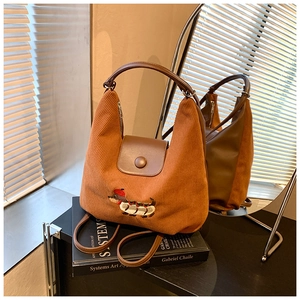 Dettaglio di una borsa hobo in velluto marrone con ricamo a bassotto e manico in pelle