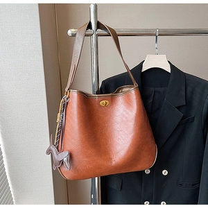 Detailansicht der karamellbraunen Totebag mit goldenem Schloss und Hunde-Anhänger