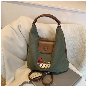 Dettaglio della borsa hobo in velluto verde con finiture in pelle e ricamo cane