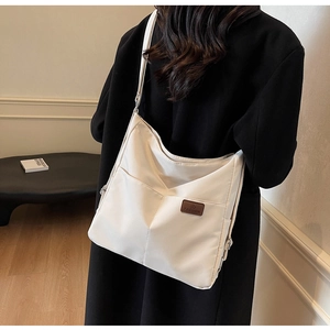 Close-up of a white canvas shoulder bag featuring a fashion leather tag and spacious pockets