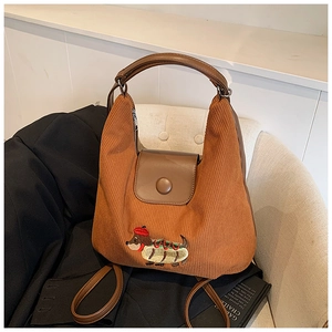 Borsa a tracolla in velluto a coste marrone con ricamo bassotto su una sedia