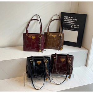 Detalle de cuatro bolsos tote retro en granate y marrón con textura tejida y logo dorado