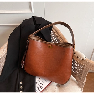 Detailed close-up of retro caramel bucket bag with a golden oval twist lock and soft texture