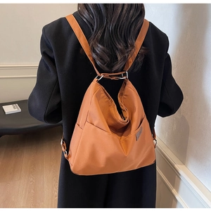 Detail view of large orange canvas backpack with drawstring and adjustable silver buckles
