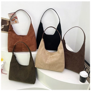 Selection of five suede tote bags in various colors displayed on a minimalist white stage