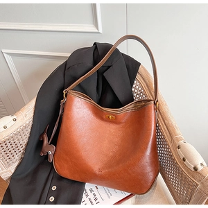 Close-up of vintage brown leather bag featuring a gold twist lock and oil wax texture