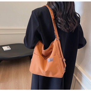 Detailed back view of a burnt orange canvas bucket bag featuring a side pocket and logo