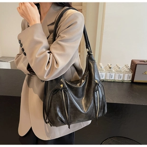 Detail of black large capacity hobo bag with sleek leather texture and tassel zipper