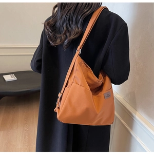 Detailed view of an orange canvas tote bag showing the side fashion label and durable texture