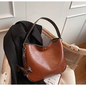 Detail of dark brown leather bucket bag with gold twist lock and a cute dog charm