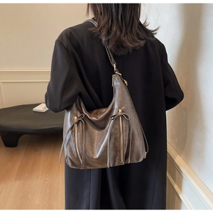 Detail of dark brown PU leather tote bag with vintage texture and bow zipper details