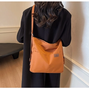 Detail view of large orange canvas crossbody bag featuring functional front pockets and strap