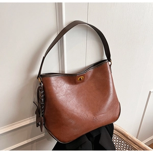 Detail of vintage brown leather bucket bag with gold clasp and elegant floral scarf