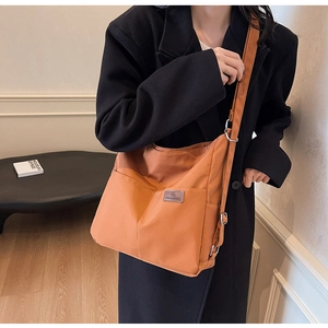 Detail of orange canvas crossbody bag featuring functional front pockets and fashion tag