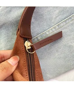 Detail of front zipper with gold hardware and leather pull on brown suede shoulder bag