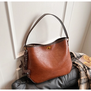 Detail of vintage brown shoulder bag with gold twist lock and horse charm on a chair