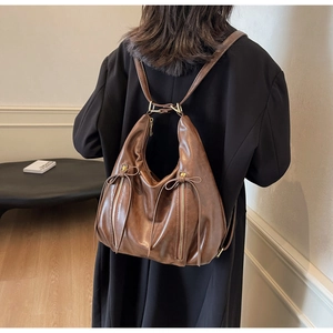 Detail of a brown faux leather backpack showing soft texture and bow zipper accents