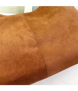 Detailed macro view of the caramel suede fabric texture and double-stitch sewing process