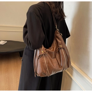 Detail of vintage brown PU leather hobo bag with metal zipper and bow drawstring detail