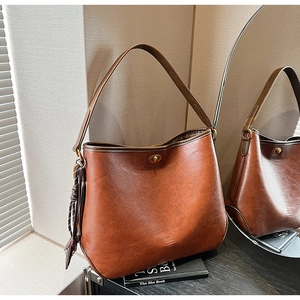 Detail of vintage brown tote bag with metal twist lock and decorative side tassel charm