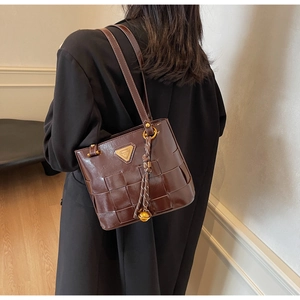 Detalle del bolso cubo retro trenzado con borlas y colgantes dorados