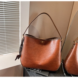 Close-up of brown vintage hobo bag with metal twist lock and decorative woven tassel detail