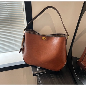 Close-up of vintage brown leather handbag with brass twist lock and litchi texture detail