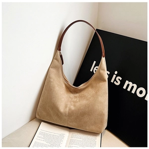 Detail of a large brown suede hobo bag with a dark leather strap and top zipper closure