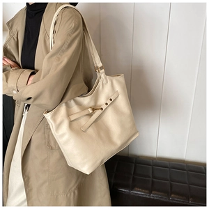 Chic beige tote bag in PU leather featuring gold buckle detail, styled with a trench coat