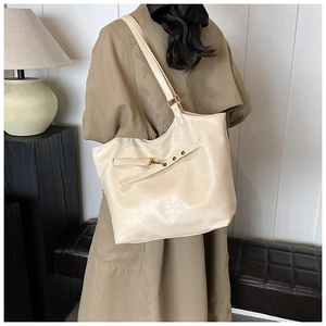 Detail view of a large beige PU leather tote bag with decorative straps and metal buckles