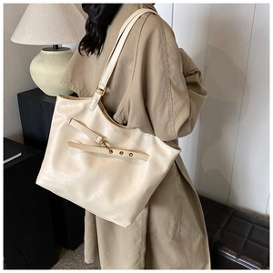 Close-up of a large cream tote bag with adjustable metal buckle strap and PU leather texture