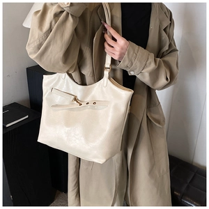 Close-up of cream PU leather tote bag with gold buckle detail on a khaki trench coat