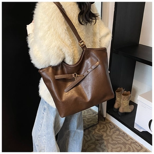 Detail of vintage brown tote bag showing smooth synthetic leather texture and gold hardware