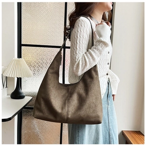Detail of a large brown hobo bag in matte suede texture showing its wide shoulder strap