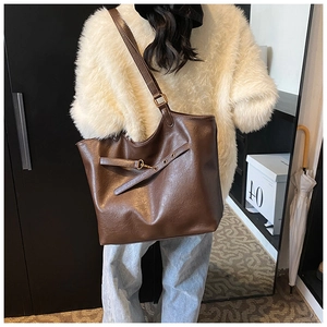 Detailed view of the large brown vintage tote bag with metal buckles on shoulder