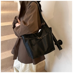 Detail view of large black leather tote bag with adjustable strap and gold buckle