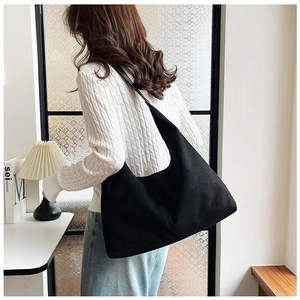 Close-up of matte black hobo tote bag with wide strap worn by a female model