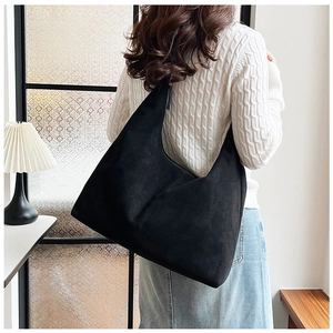 Macro detail of the matte black faux suede shoulder bag showing large capacity texture
