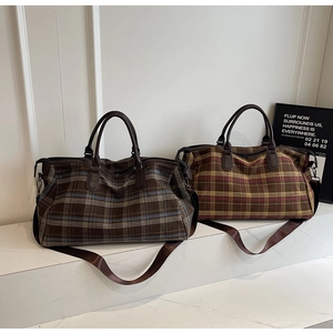 Détail de sacs de voyage à carreaux avec poignées en cuir et bandoulière amovible