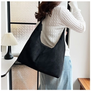 Detail of a large black hobo shoulder bag in matte faux suede material on a female model