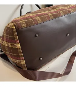 Détail du sac de voyage à carreaux avec base en cuir et pieds de protection en argent
