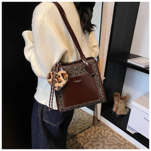 Detail of contrast tote bag with leopard print, heart charm and brown leather pocket