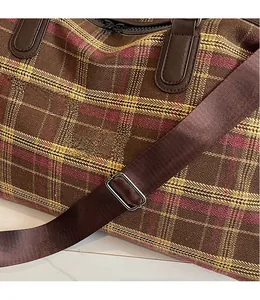 Détail de la bandoulière réglable et du tissu à carreaux marron du sac de voyage