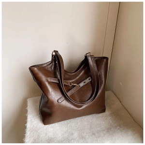 Detail view of large brown tote bag with gold hardware buckle and smooth PU leather texture