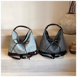 Dual-use bucket tote bags with leather bows and mixed textures on stone steps