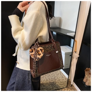 Detail of brown leather tote bag with leopard print stitching and plush heart charm