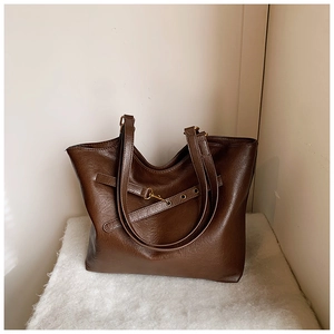 Detailed macro view of dark brown textured leather tote bag with vintage gold metal buckles