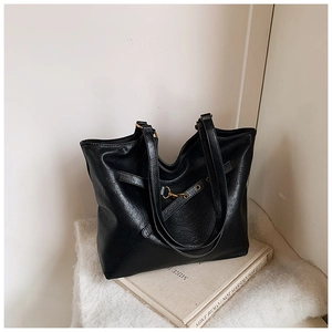 Close-up of black retro tote bag with textured faux leather and golden buckle detail