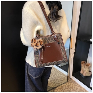 Close-up of brown leather tote bag with leopard print pocket and heart plush charm