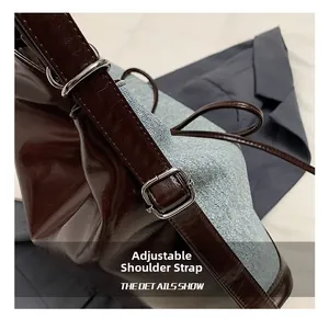 Detail of adjustable shoulder strap with silver buckle on brown leather and denim tote bag